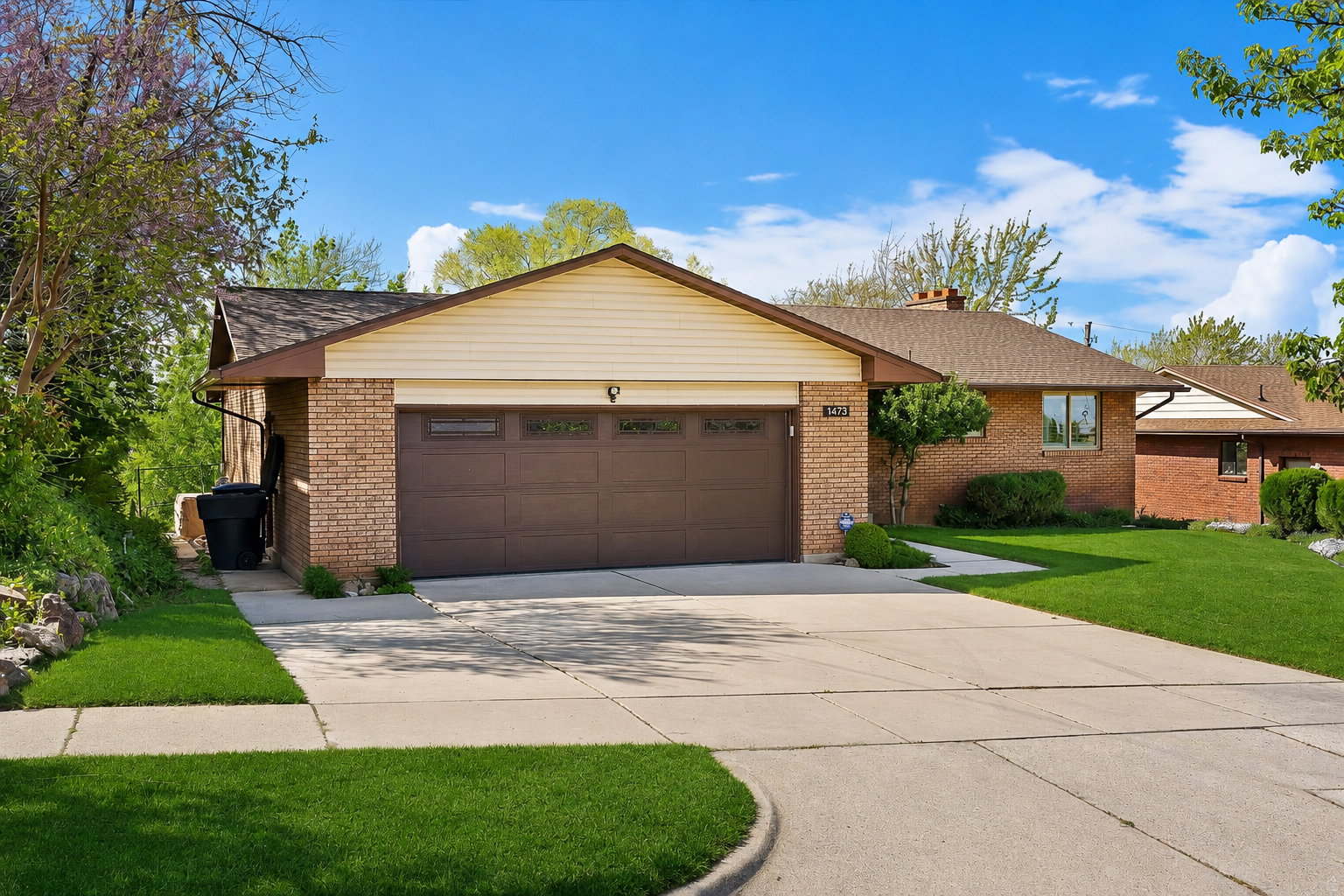 Brick exterior with a two-car garage featuring a brown door with integrated windows