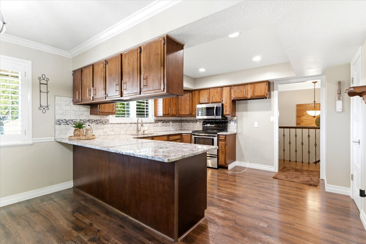 Kitchen featuring wood-finish flooring, granite countertops, and wood cabinetry
