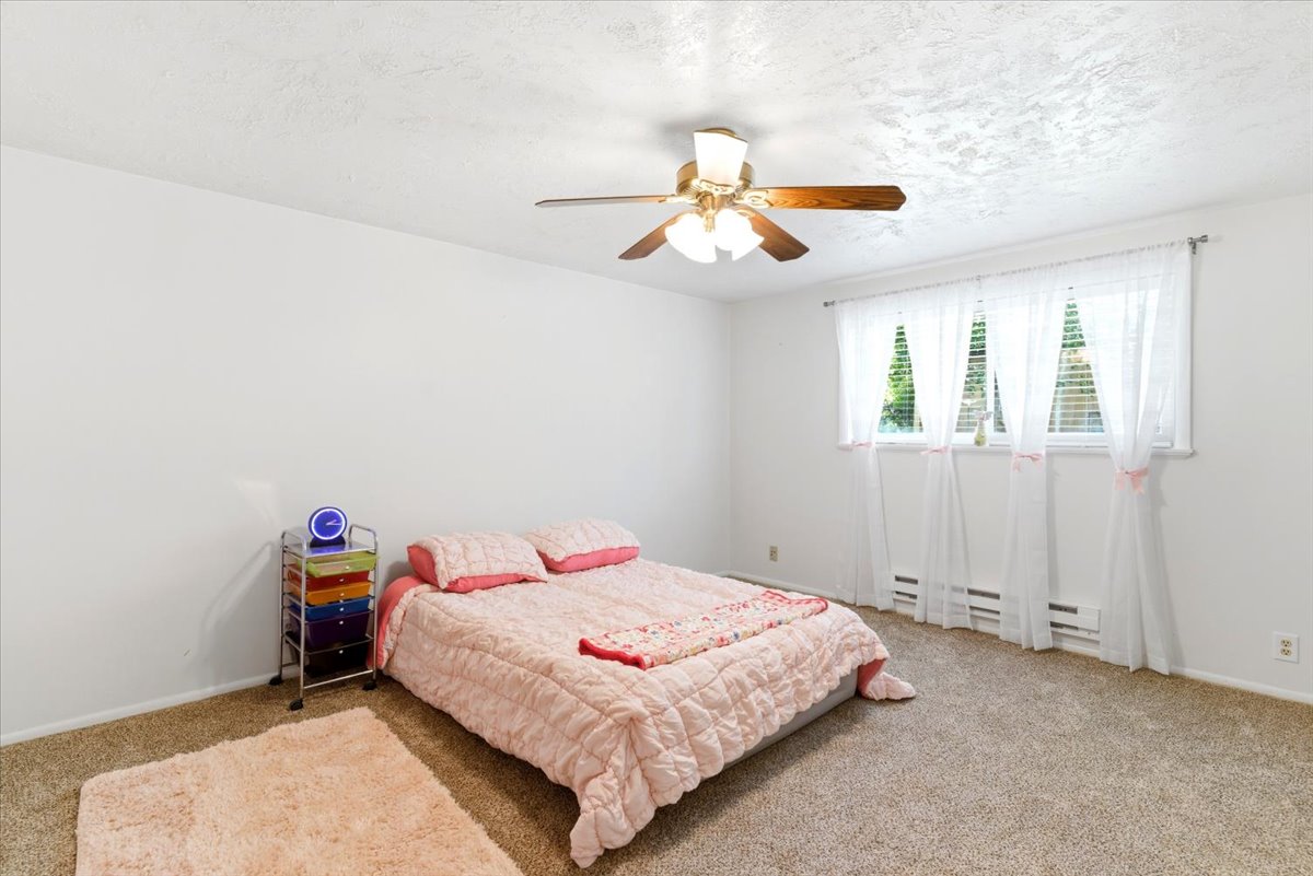 Spacious bedroom featuring neutral wall paint, textured ceiling, and carpeted flooring