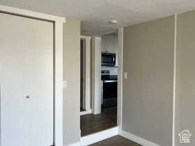 Unfurnished bedroom with a closet, dark wood-type flooring, and a textured ceiling