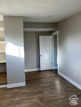 Unfurnished bedroom with dark wood-style flooring and a textured ceiling