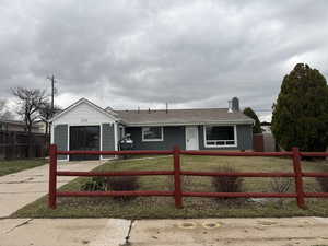 Single story home with a fenced front yard, a chimney, a shingled roof, and brick siding