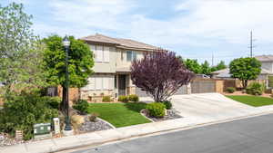 View of front of property featuring concrete driveway, stucco siding, stone siding, and a garage
