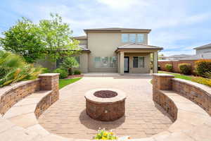 Rear view of property featuring a fire pit, a patio area, stucco siding, and a fenced backyard