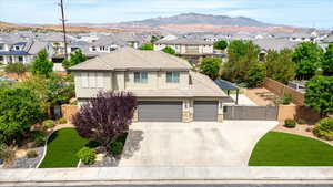 View of front facade with a gate, stone siding, driveway, and stucco siding