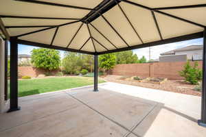 Fenced backyard with a patio area, a garden, and a gazebo