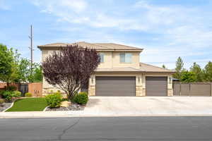 View of front facade with stone siding, a tiled roof, stucco siding, and driveway