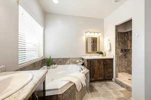 Full bathroom with two vanities, tiled shower, and a tub with jets