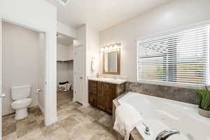 Bathroom featuring vanity, a jetted tub, and a spacious closet