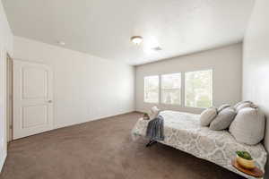 Bedroom featuring dark colored carpet and a textured ceiling