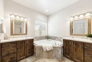Bathroom featuring two vanities and a garden tub