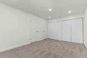 Unfurnished bedroom featuring multiple closets, carpet, and recessed lighting