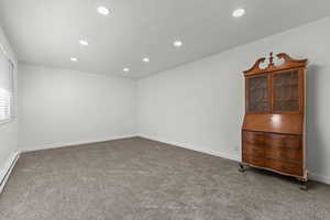 Unfurnished room featuring dark carpet, recessed lighting, and a baseboard radiator