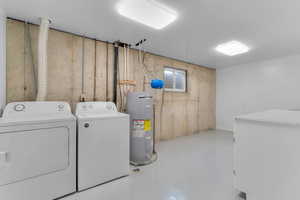 Laundry area featuring finished concrete floors, water heater, and washer and clothes dryer