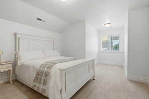 Bedroom featuring light carpet and vaulted ceiling