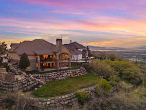 View of front of home featuring a chimney, a patio, a balcony, stucco siding, and a mountain view