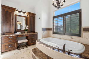 Full bath featuring vanity, a garden tub, and a chandelier