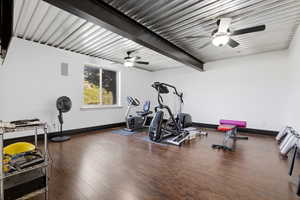 Workout area featuring ceiling fan and beamed ceiling