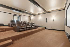 Cinema featuring light colored carpet and beam ceiling