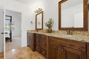 Full bath featuring double vanity, stone tile floors, and connected bathroom