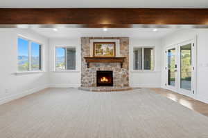 Unfurnished living room with french doors, a fireplace, light colored carpet, a mountain view, and recessed lighting