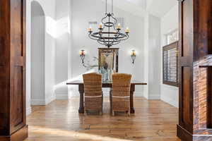 Dining space with lofted ceiling, light wood-style flooring, and a chandelier