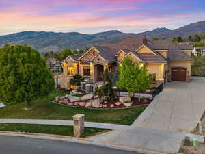 View of front of home with concrete driveway, a mountain view, an attached garage, and stone siding