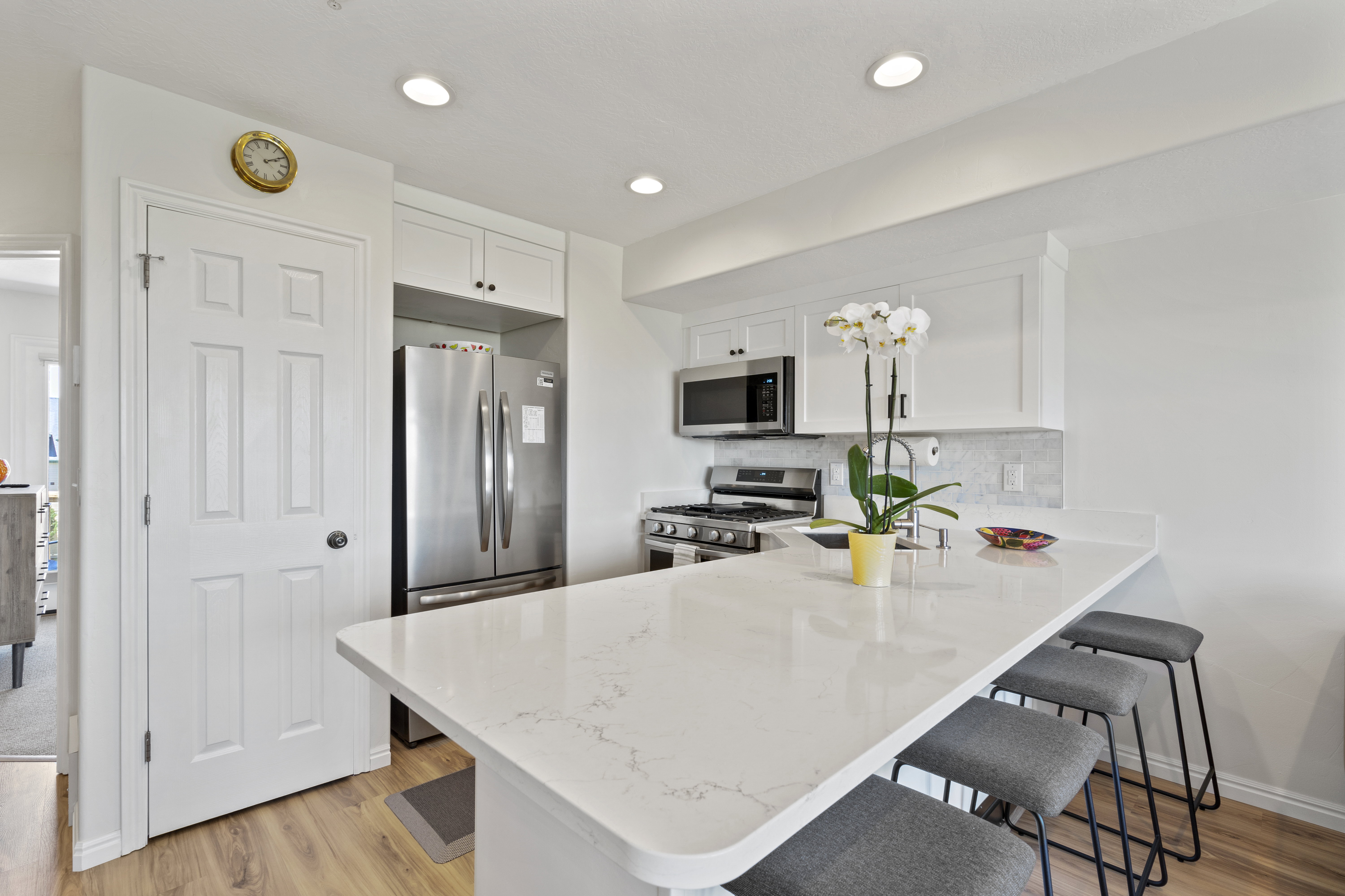 Kitchen featuring a breakfast bar area, a peninsula, light wood-style flooring, stainless steel appliances, and light stone counters