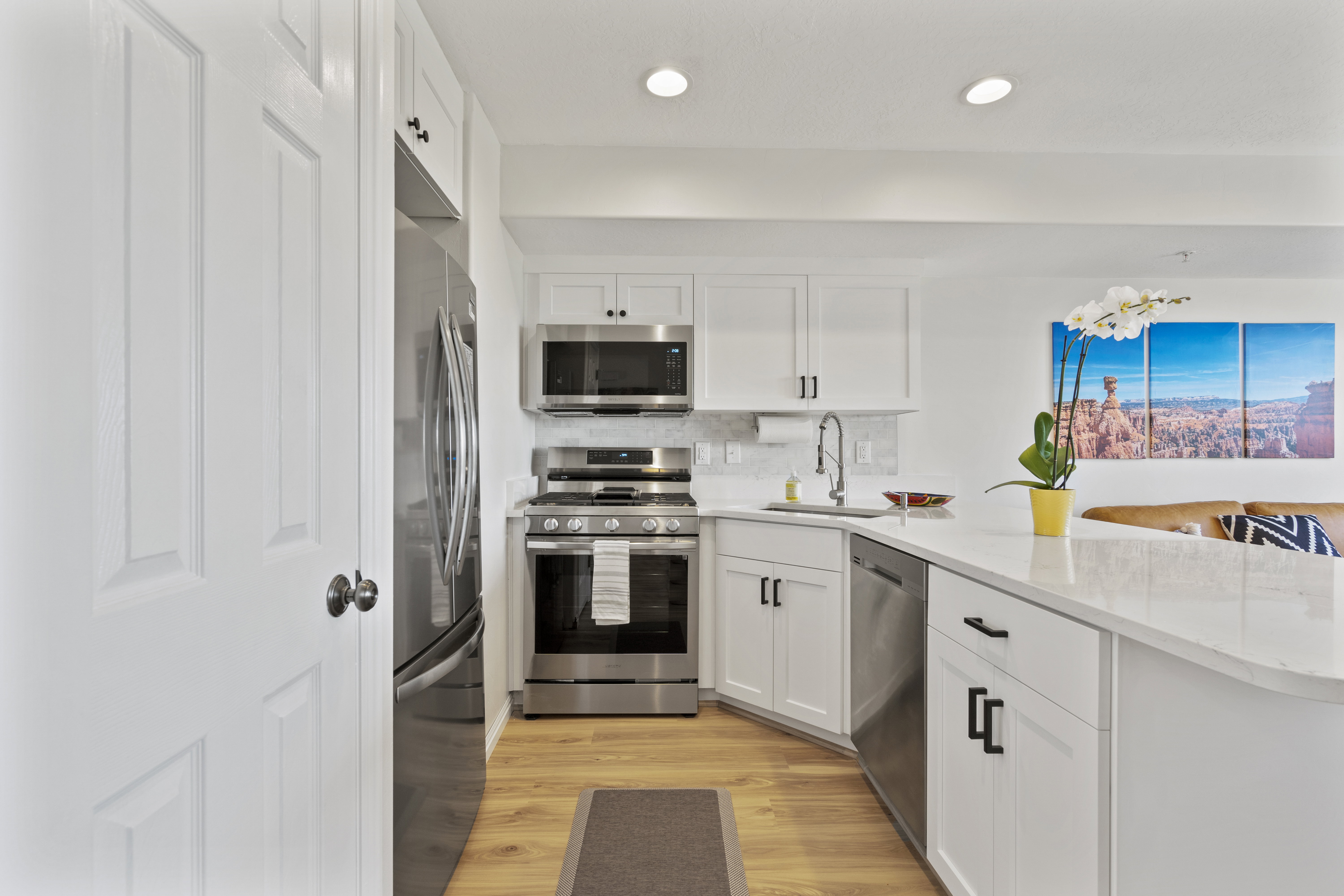 Kitchen with stainless steel appliances, white cabinets, a peninsula, and light wood finished floors