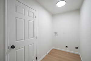 Laundry area with light wood finished floors, hookup for a washing machine, and electric dryer hookup