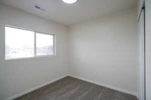 Unfurnished room with baseboards and dark carpet