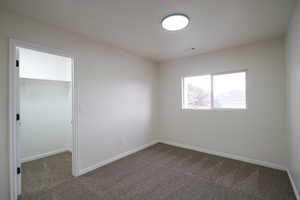 Unfurnished room with dark carpet and baseboards