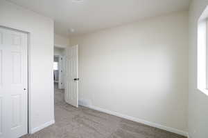 Unfurnished bedroom with light carpet and baseboards