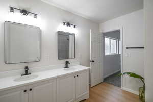 Bathroom with double vanity and light wood finished floors