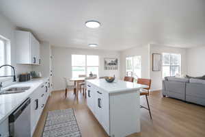 Kitchen with white cabinetry, a breakfast bar, open floor plan, and light wood-style floors