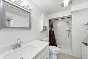 Full bathroom with vanity, a stall shower, and light tile patterned flooring