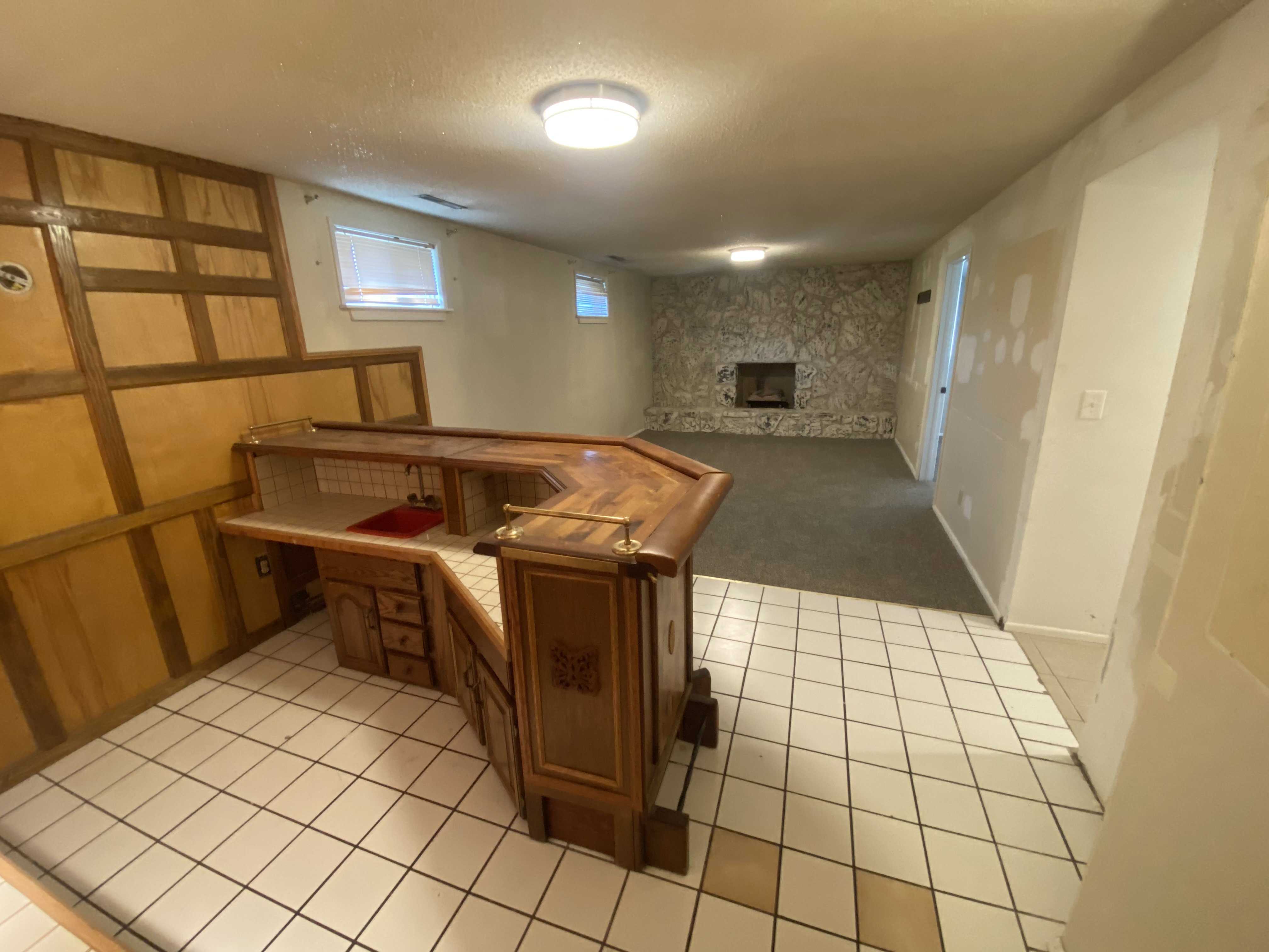 Wet bar featuring wood-finish cabinetry, built-in sink, and tile flooring