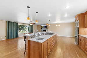 Kitchen featuring light stone countertops, wood finish cabinets, a ceiling fan, a breakfast bar, and light wood-type flooring