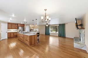 Kitchen featuring wood finish cabinetry, open floor plan, hanging lights, a kitchen breakfast bar, and ceiling fan
