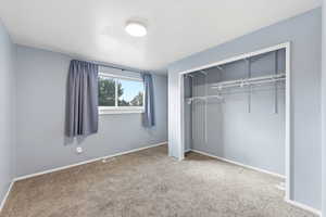 Unfurnished bedroom featuring light carpet and a closet