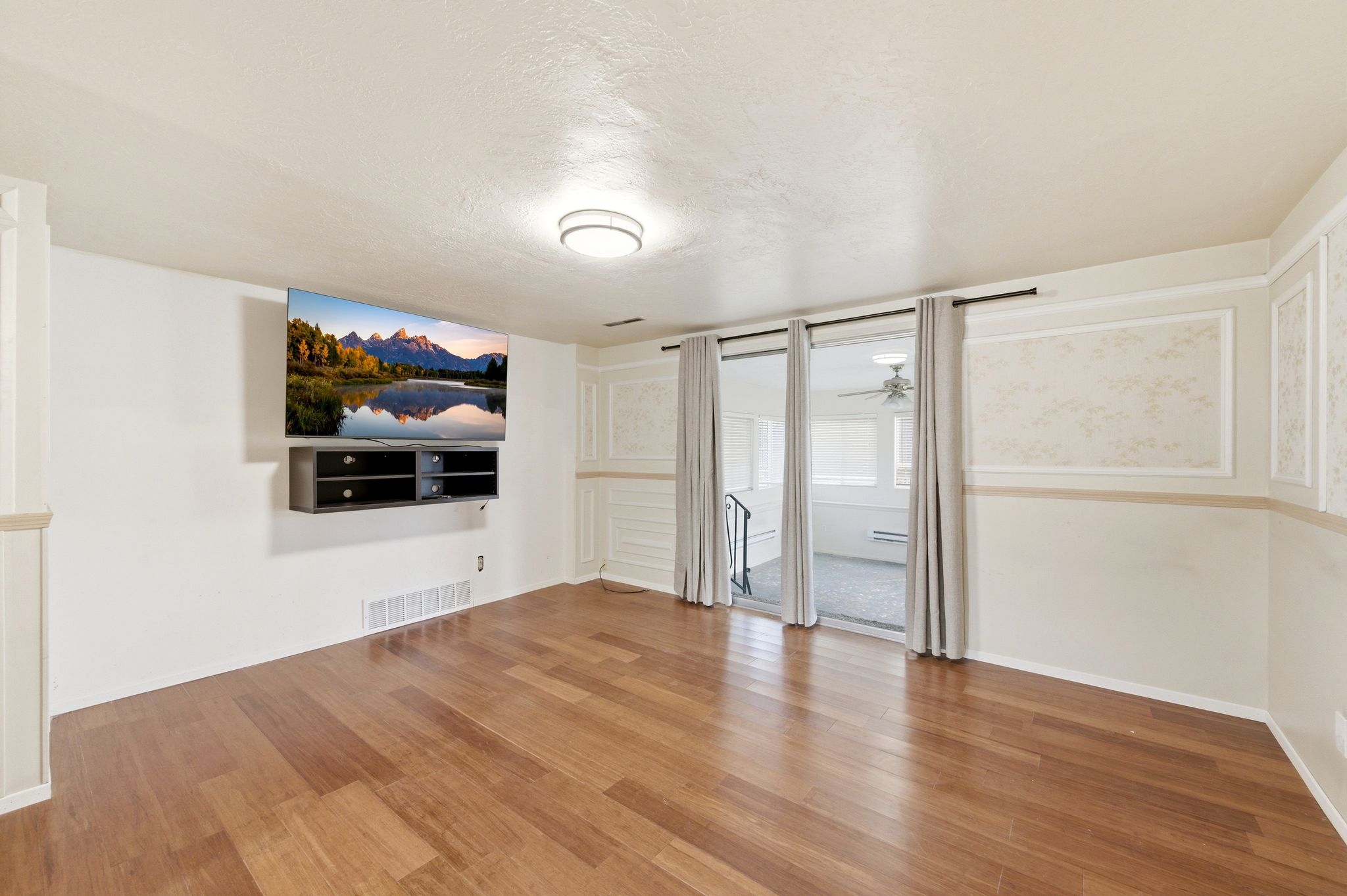 Unfurnished living room featuring light wood-style flooring, a textured ceiling, and a ceiling fan