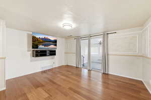 Unfurnished living room featuring light wood-style flooring, a textured ceiling, and a ceiling fan