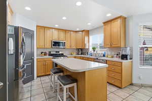 Kitchen featuring a kitchen bar, light tile patterned flooring, stainless steel appliances, recessed lighting, and light countertops