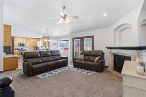 Living area featuring recessed lighting, light colored carpet, a ceiling fan, a fireplace with flush hearth, and lofted ceiling