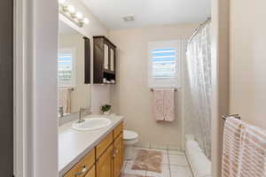 Full bathroom featuring vanity, plenty of natural light, light tile patterned flooring, and shower / bath combination with curtain