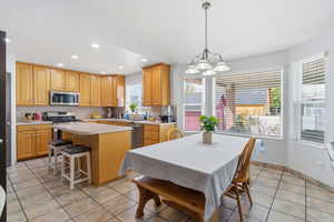 Kitchen with a kitchen island, light countertops, light tile patterned flooring, hanging lights, and a kitchen breakfast bar