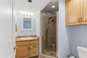 Full bath with a stall shower, vanity, and a textured ceiling