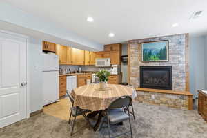 Dining area featuring light colored carpet, a stone fireplace, and recessed lighting