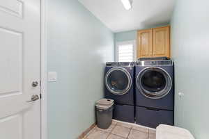 Laundry area with cabinet space, washer and clothes dryer, and light tile patterned flooring