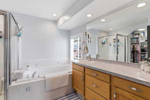 Bathroom with vanity, a garden tub, a spacious closet, and a shower stall